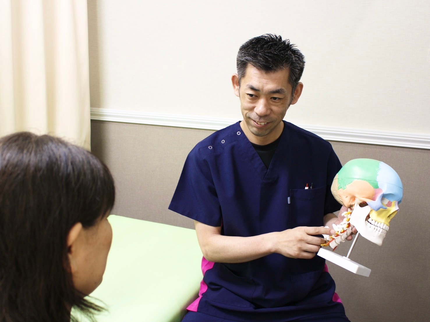 頸椎模型を使って眼精疲労について説明する柏鍼灸整骨院西口館の施術風景